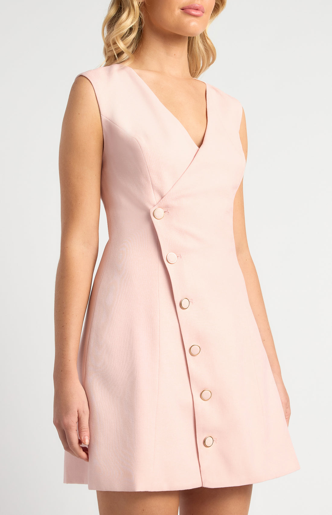 Model wearing blush pink asymmetrical button vest mini dress